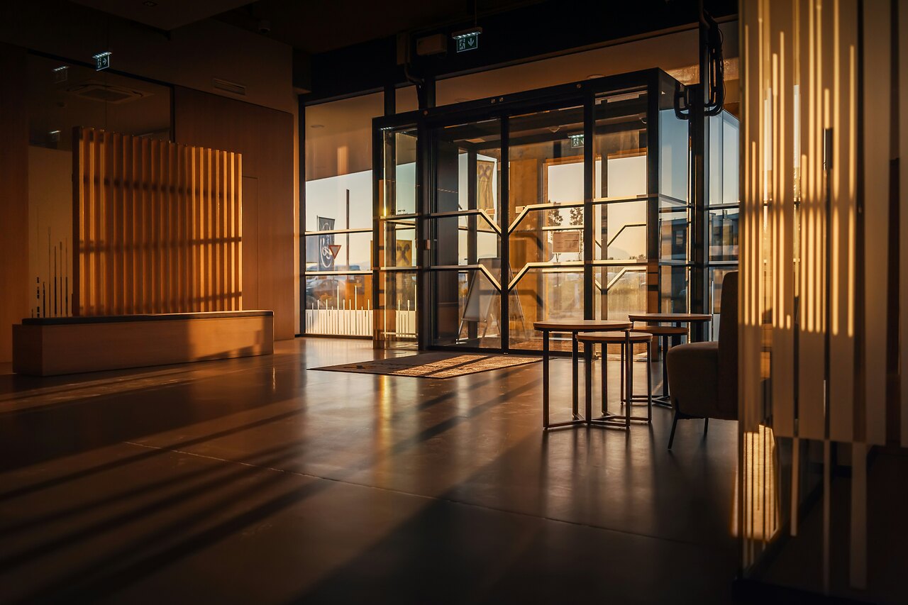 Warmer institutioneller Eingangsbereich mit Glasfront in goldenem Licht